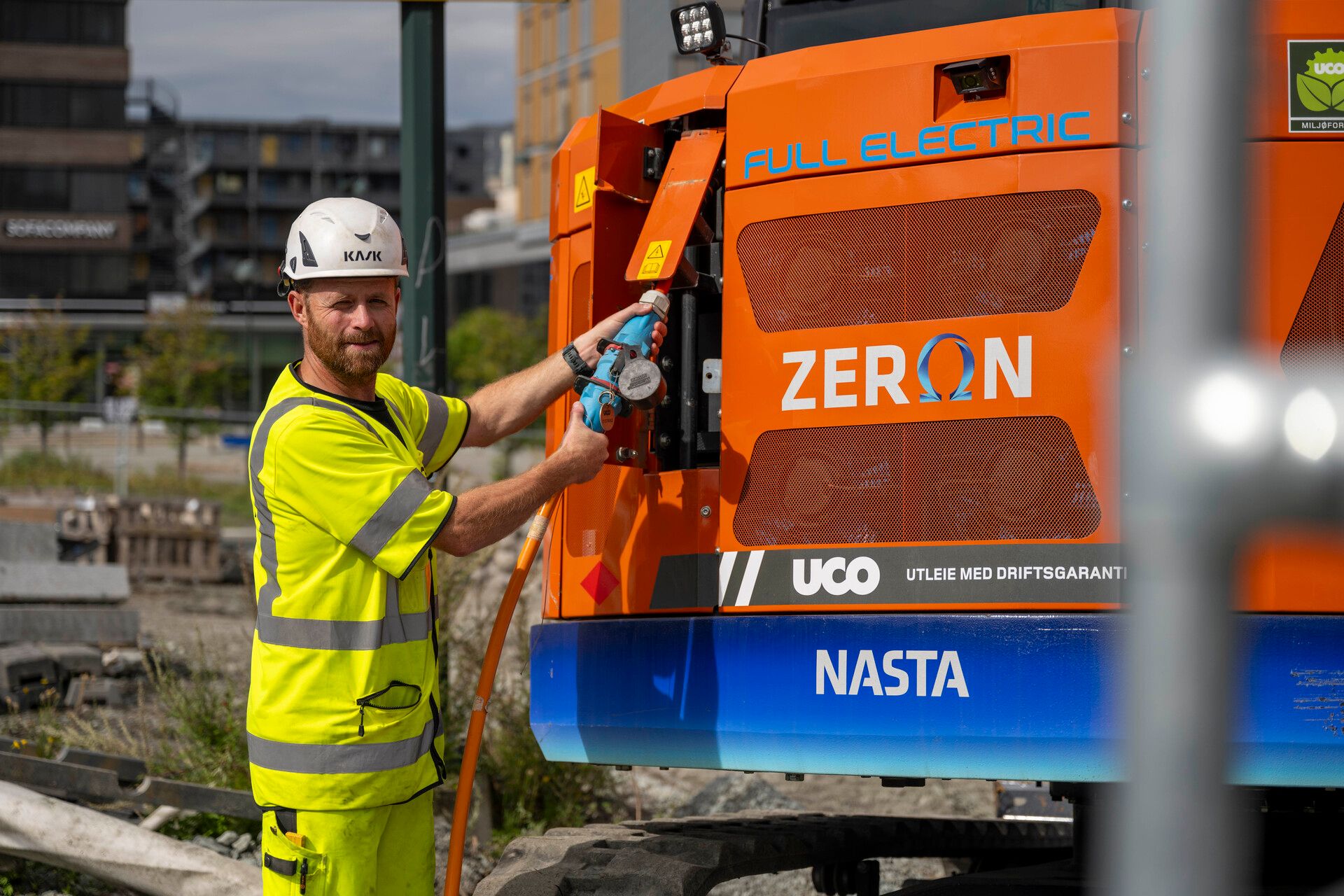 Bygningsarbeidere lader elektrisk anleggsmaskin.