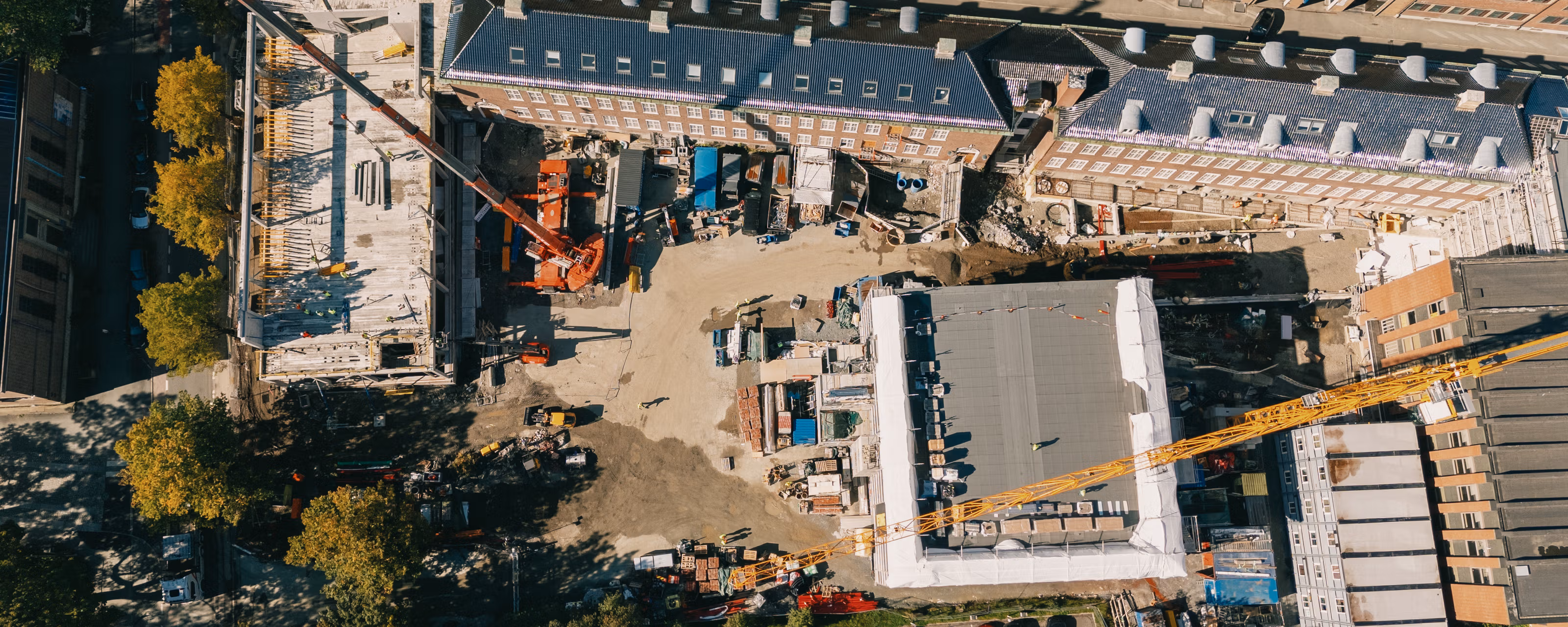 Byggeplass sett rett ovenfra med to heisekraner midt i by-bebyggelse i Trondheim sentrum.