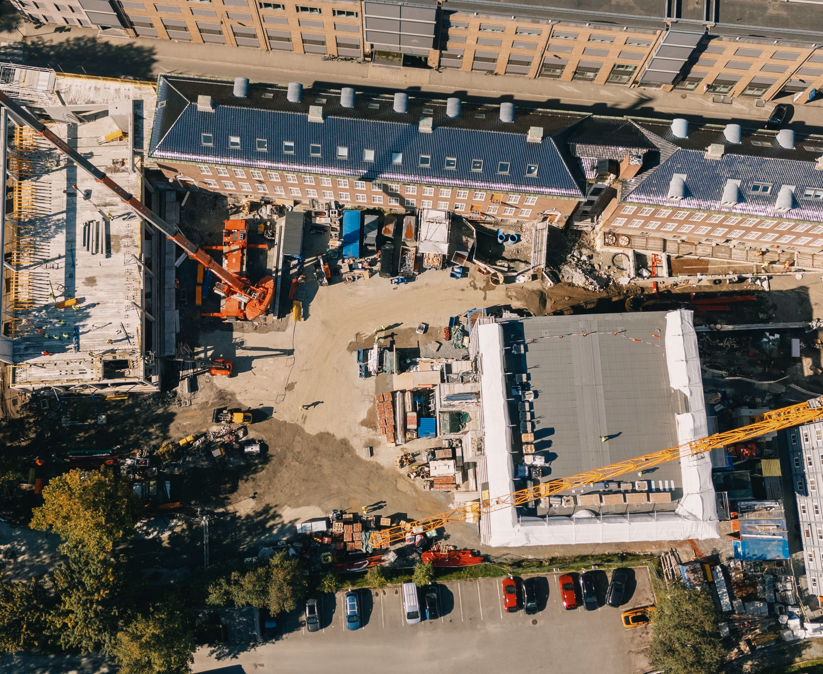 Byggeplass sett rett ovenfra med to heisekraner midt i by-bebyggelse i Trondheim sentrum.