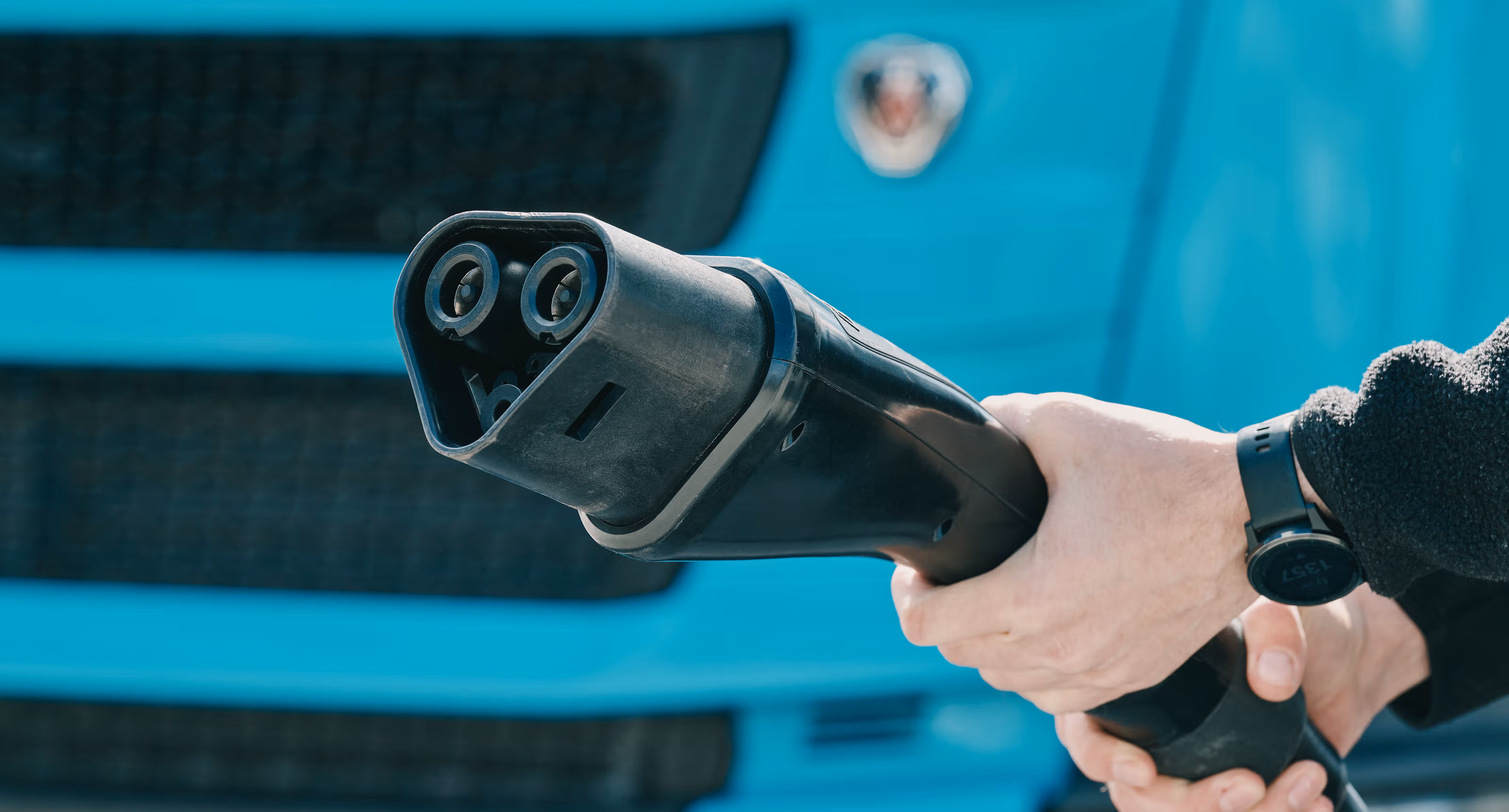 Nærbilde av to hender som holder i en ladekabel.