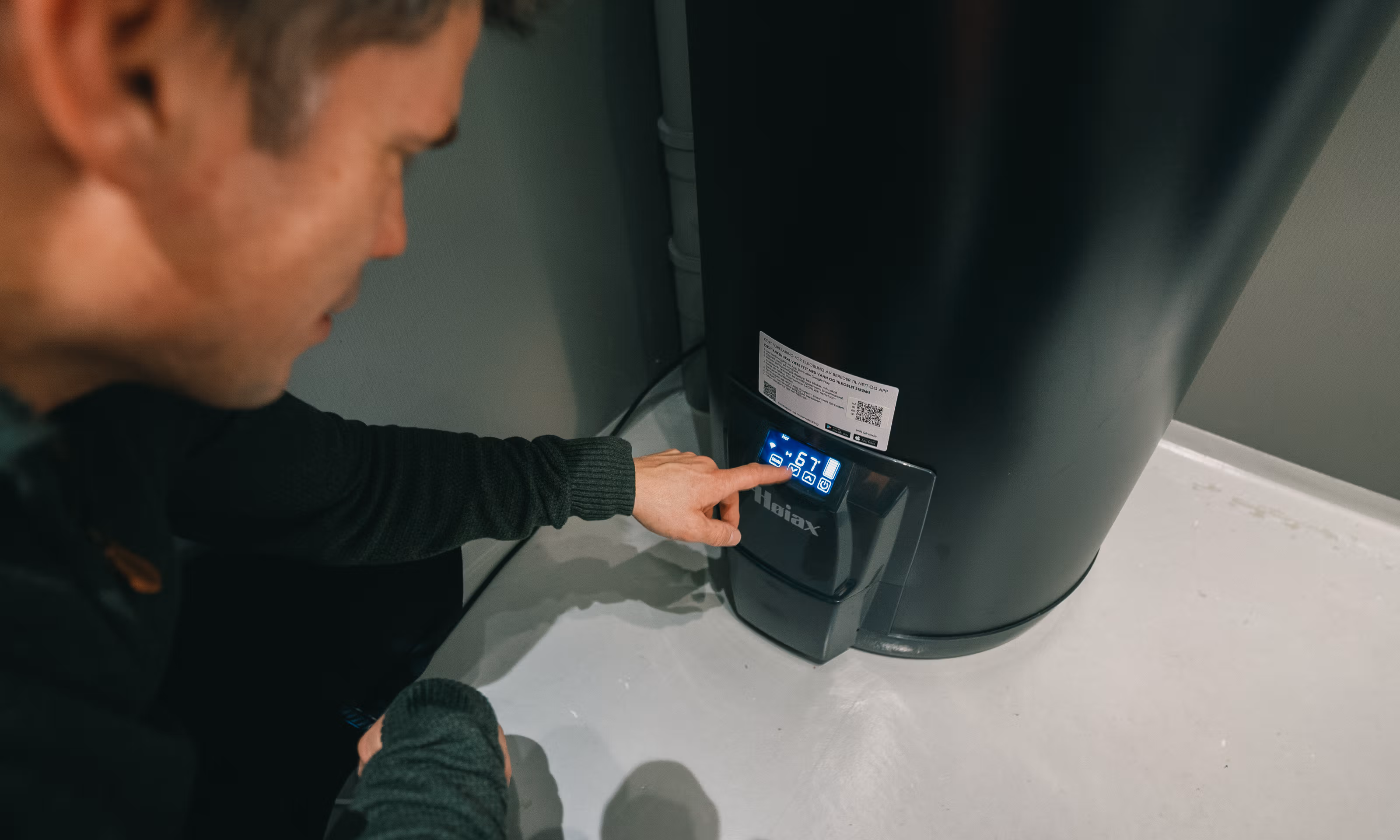 En person som trykker på en varmtvannsbereder med strømstyring.