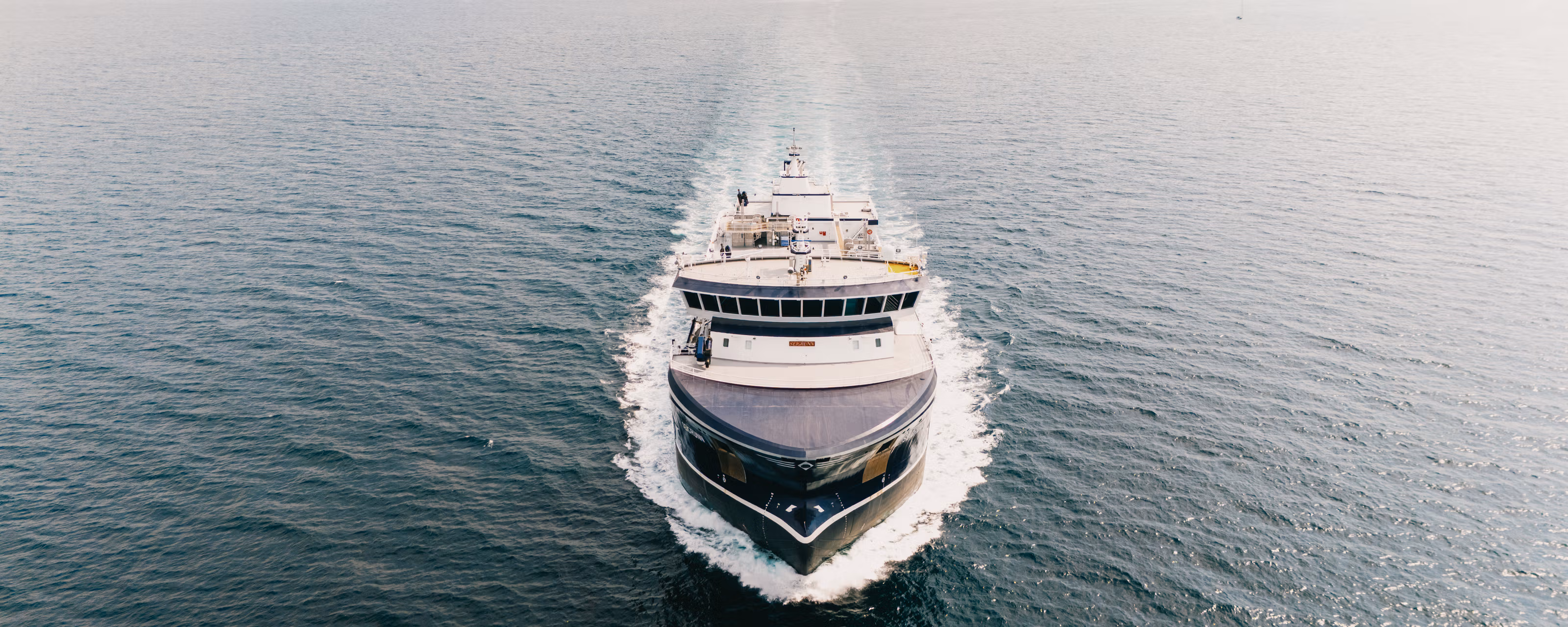 Et fartøy på sjøen sett delvis ovenfra idet nærmer seg rett imot.