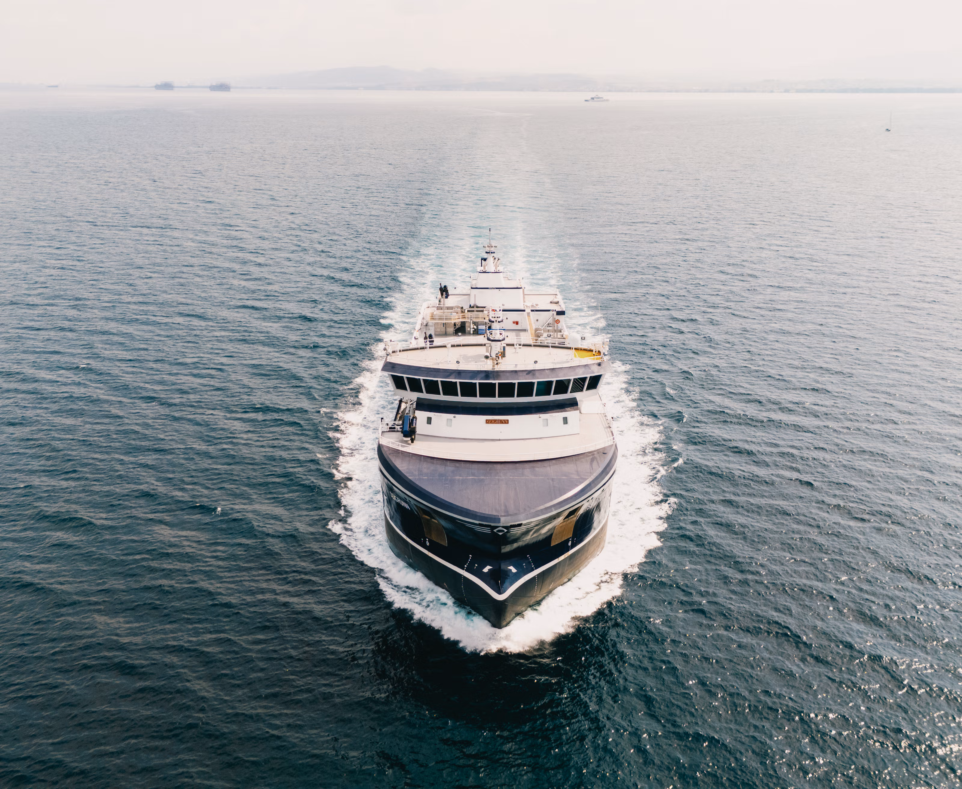 Et fartøy på sjøen sett delvis ovenfra idet nærmer seg rett imot.