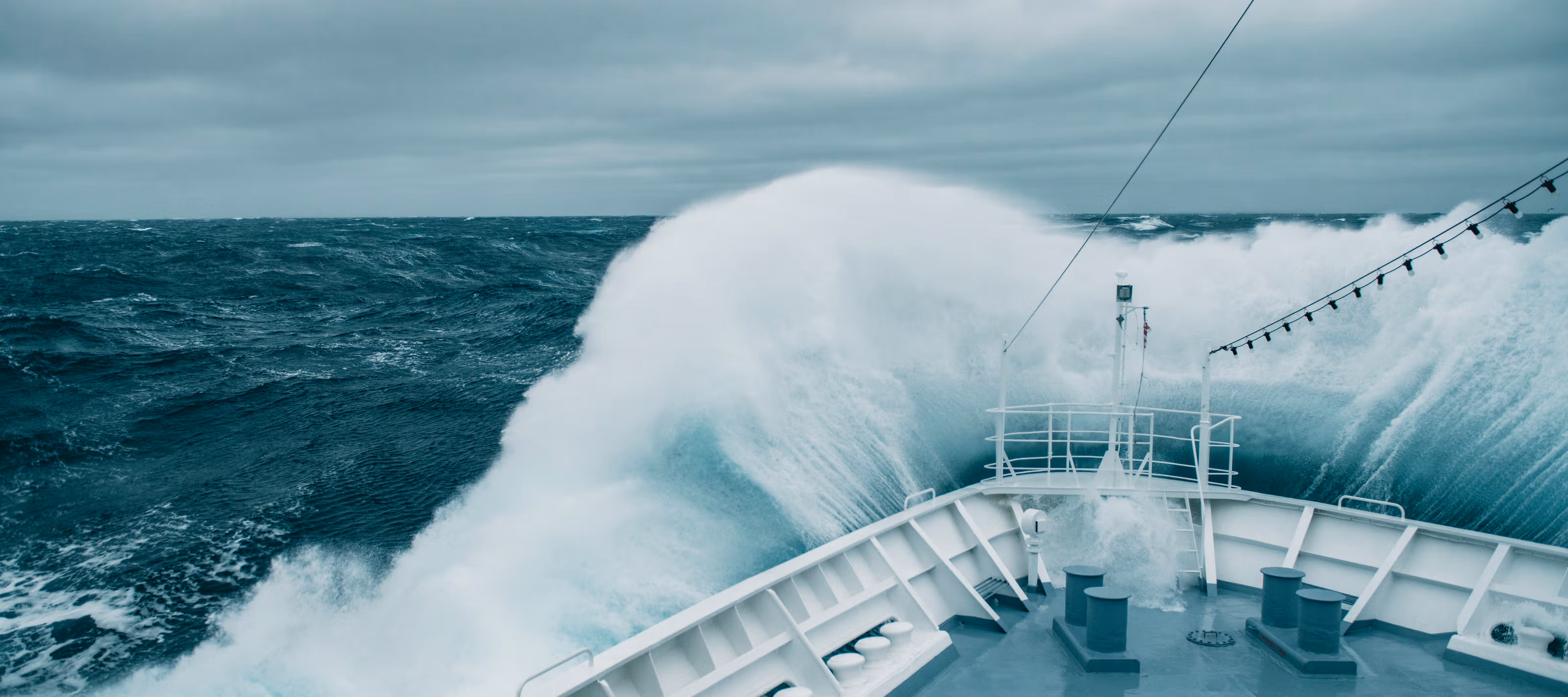 Et skip ute på havet idet en stor bølge slår inn.