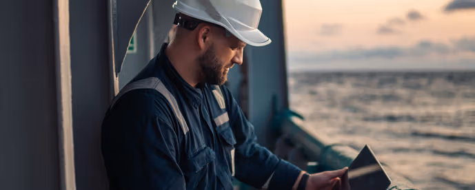En mann med hjelm ombord i et fartøy mens hans ser på datamaskin.