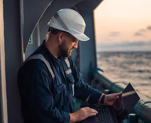 En mann med hjelm ombord i et fartøy mens hans ser på datamaskin.