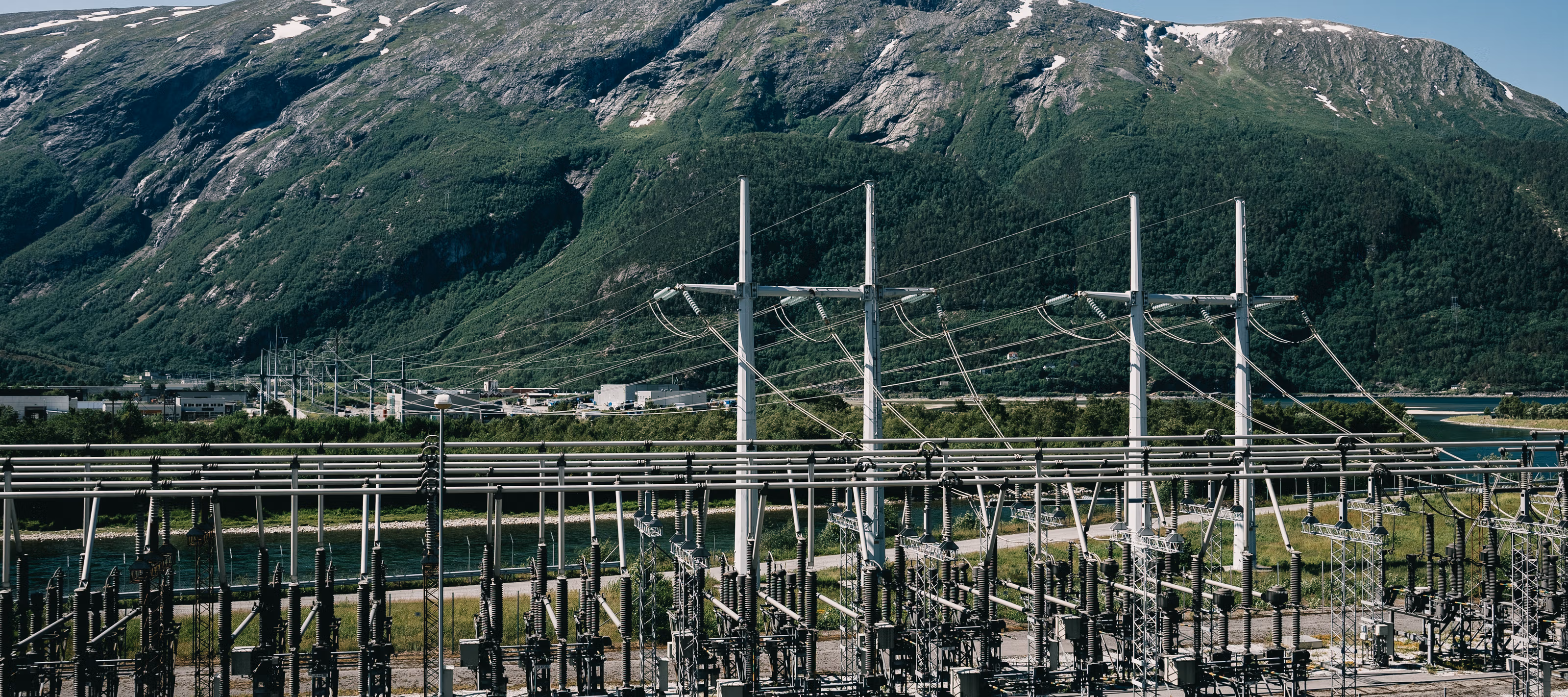 Høyspentstasjon med norsk natur og fjell i bakgrunnen.