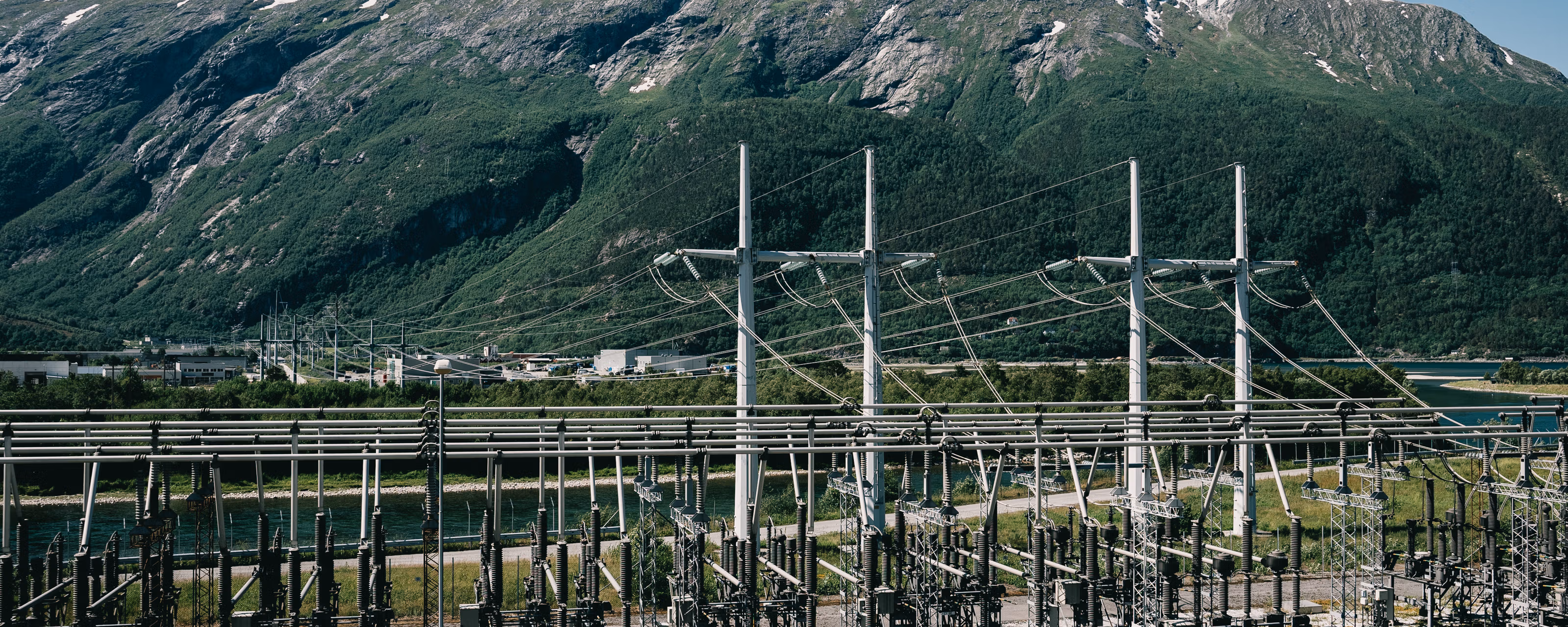 Høyspentstasjon med norsk natur og fjell i bakgrunnen.