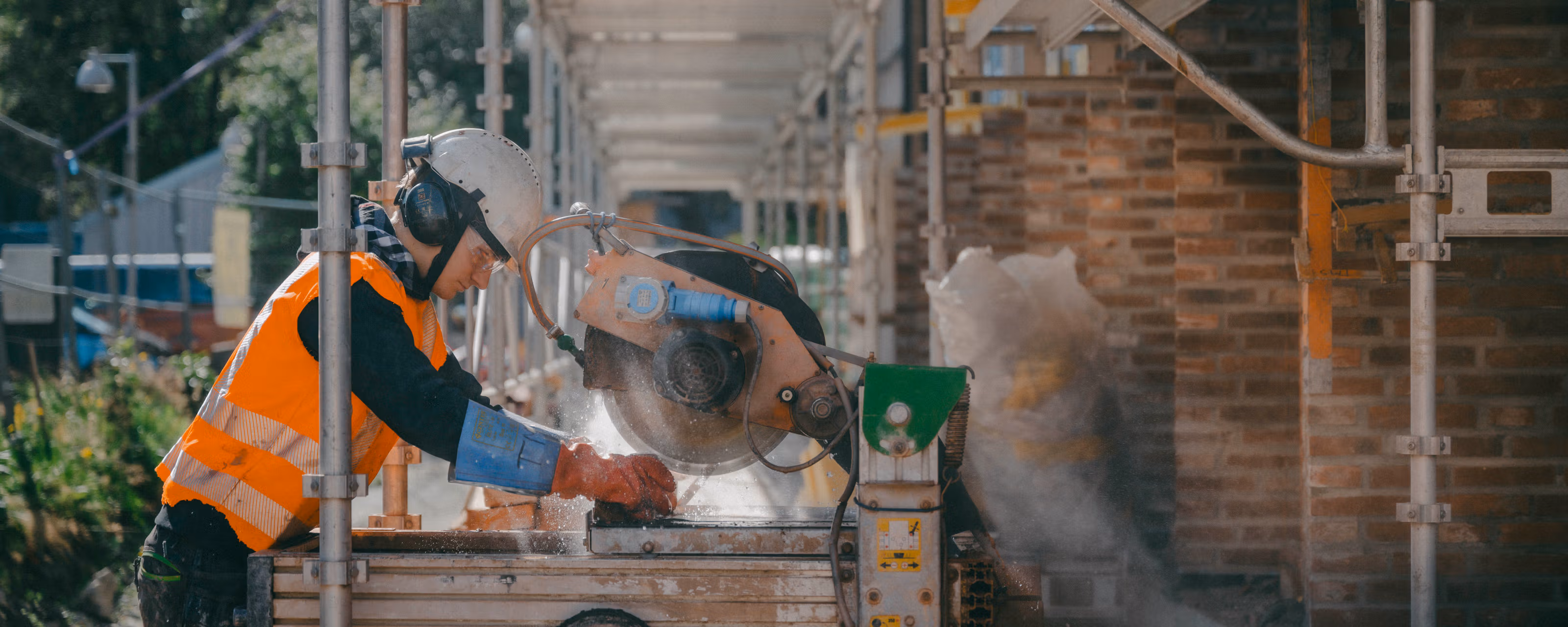 Mann i beskyttelsesutstyr kutter murstein som skal gjenbrukes.