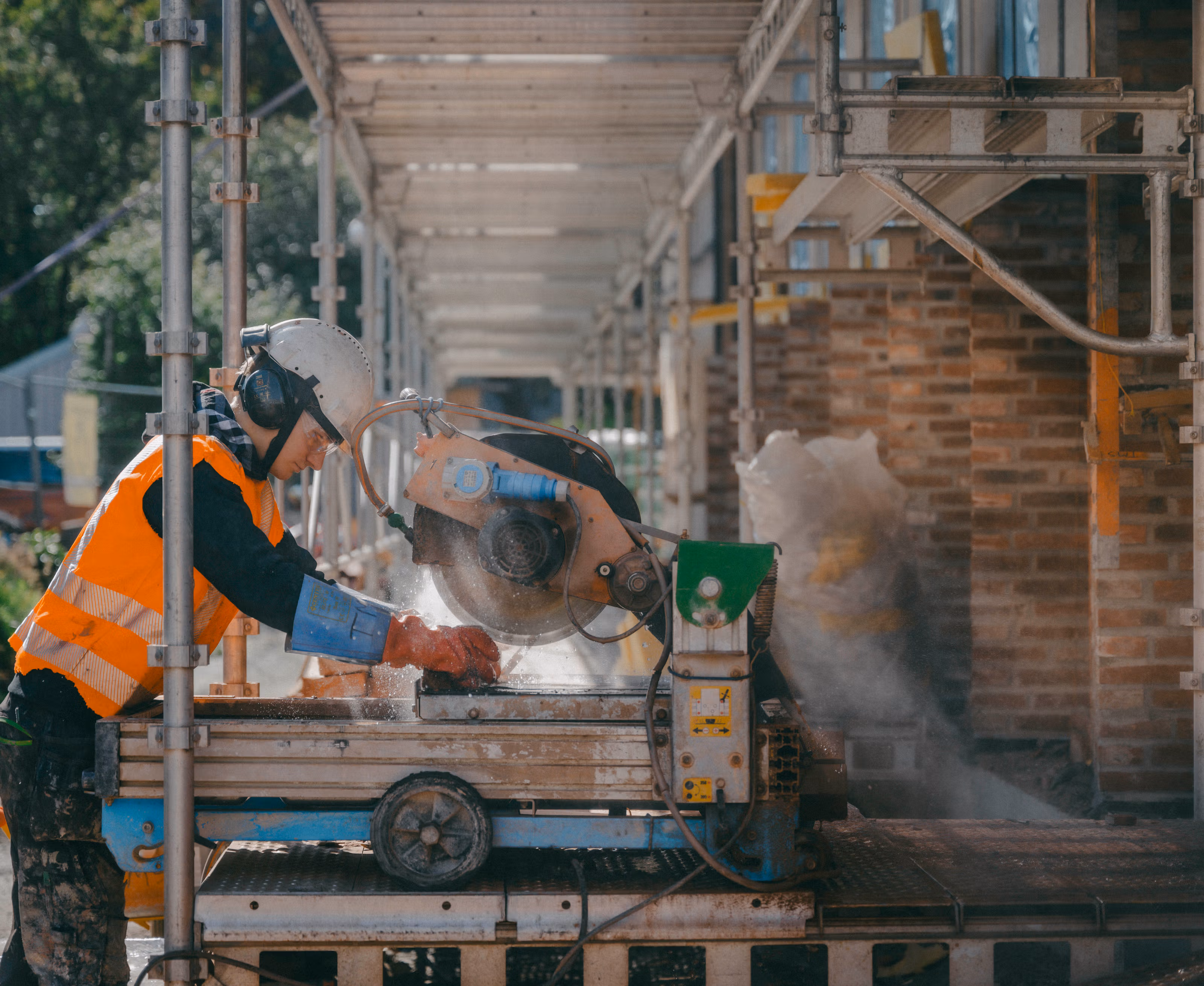 Mann i beskyttelsesutstyr kutter murstein som skal gjenbrukes.