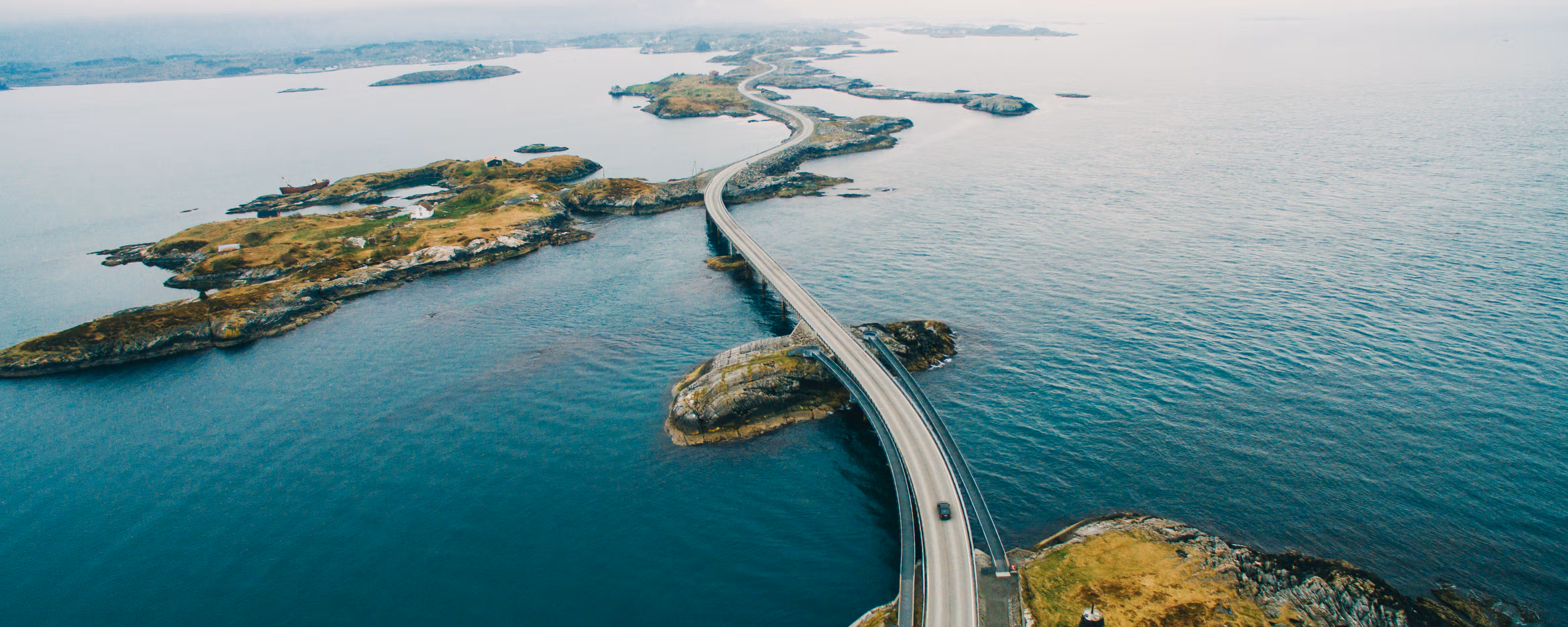 Åtte ulike elektriske lastebiler står på rekke, oppstilt foran heisekran og urbant miljø