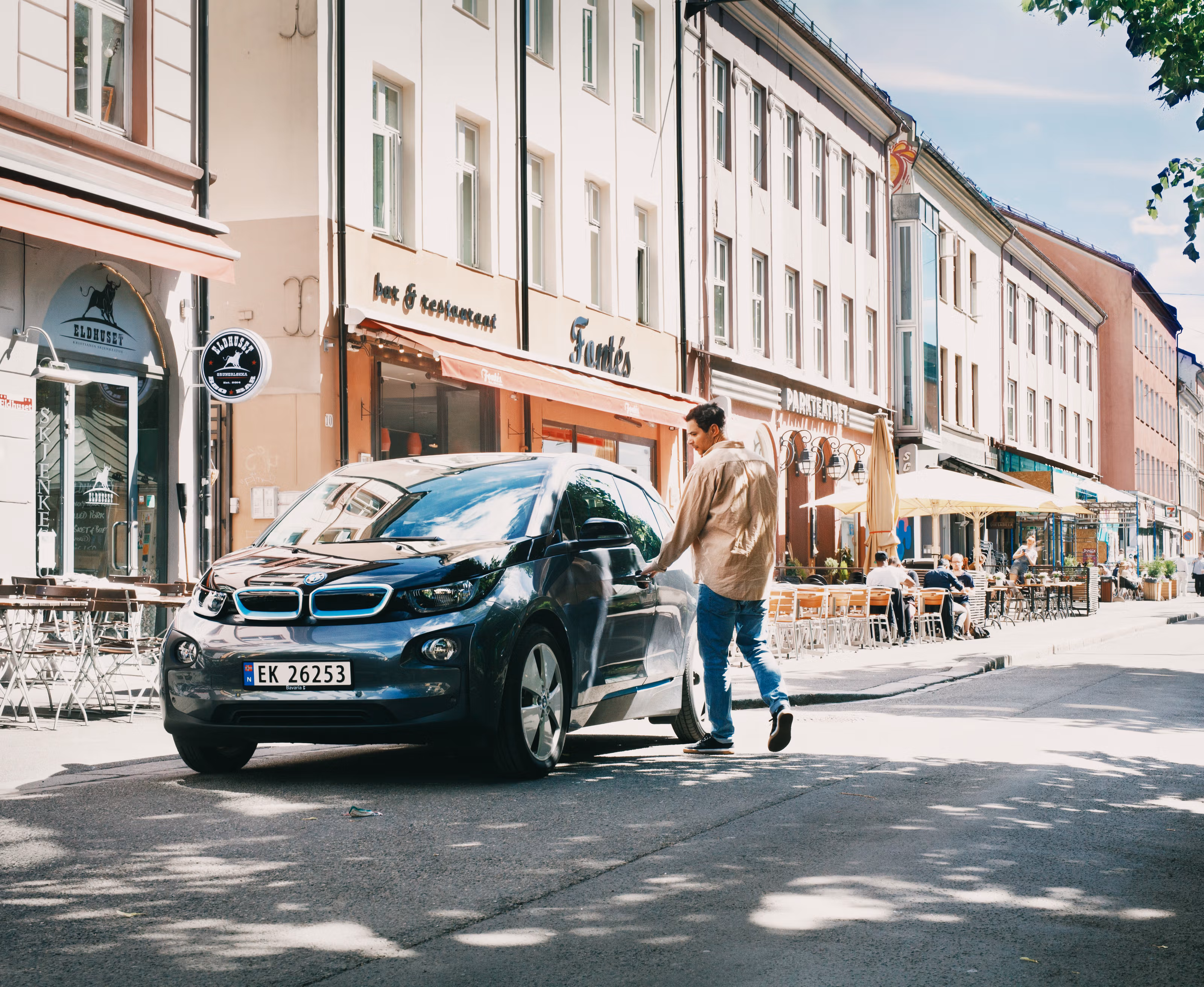 Mann som er i ferd med å åpne døren til en elektrisk bil på Grunerløkka i Oslo en sommerdag.